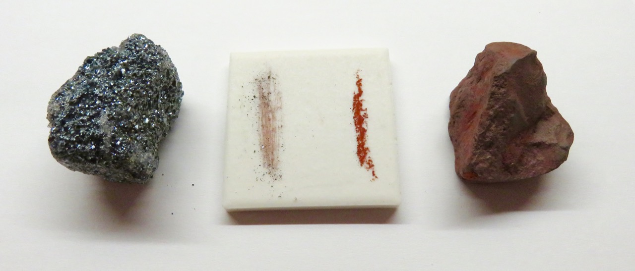 Hématite métallique et hématite terreuse de part et d’autre d’une plaque de porcelaine blanche, avec leurs deux traces rouge-brun sur la plaque